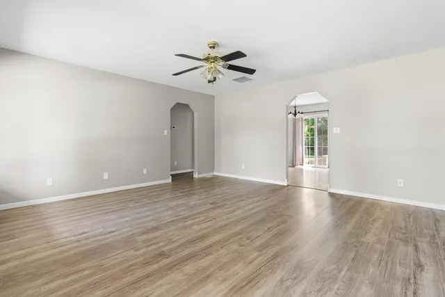 a view of empty room with wooden floor and fan