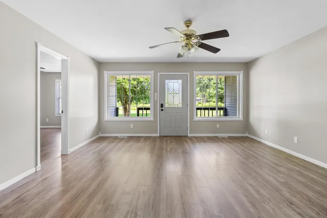a view of an empty room with a window and wooden floor