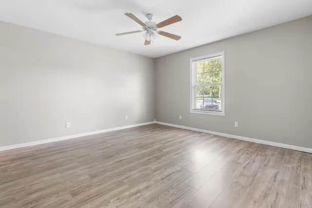 an empty room with wooden floor and windows