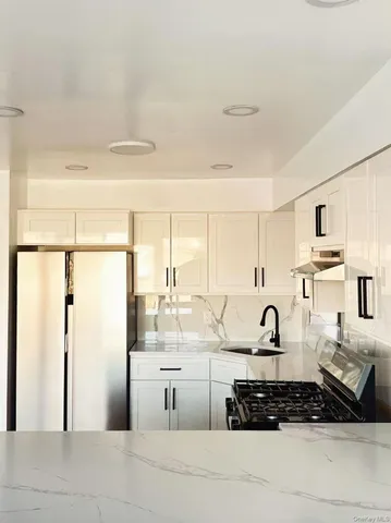 a kitchen with stainless steel appliances a refrigerator a stove and white cabinets