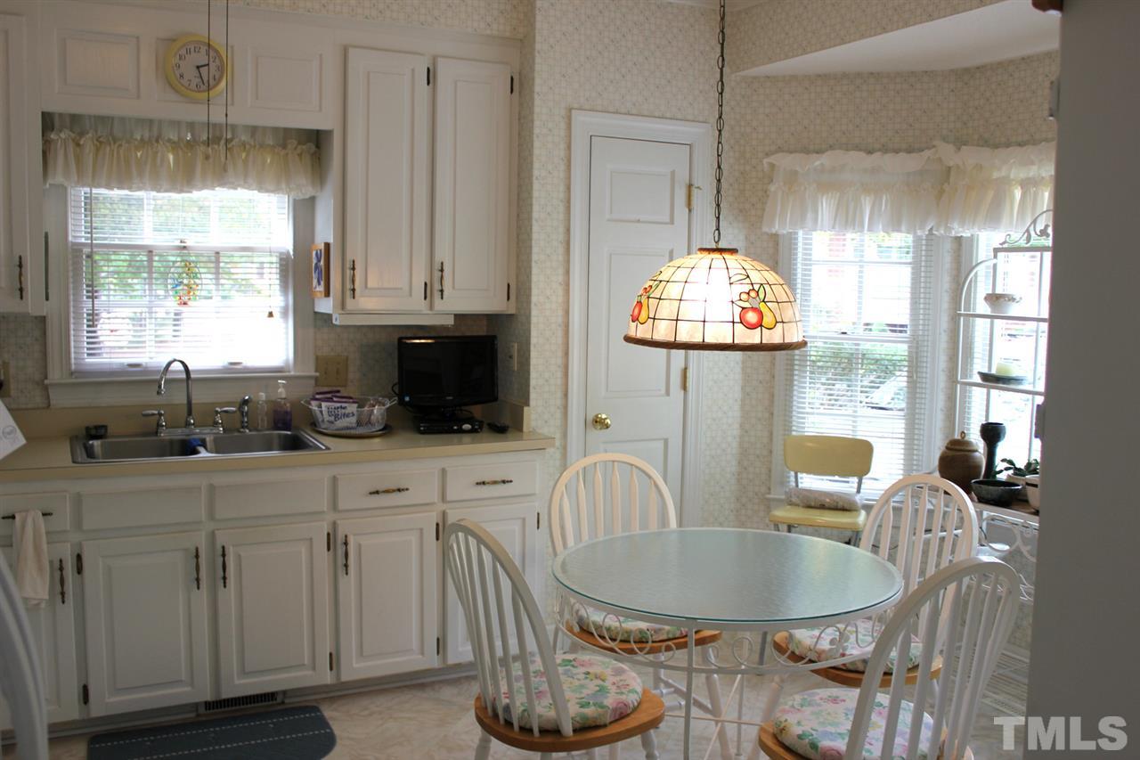 7920 Footman Way Raleigh, NC 27615 - Photo 9 of 25 a kitchen with granite countertop a stove a sink and a dining table with wooden floor