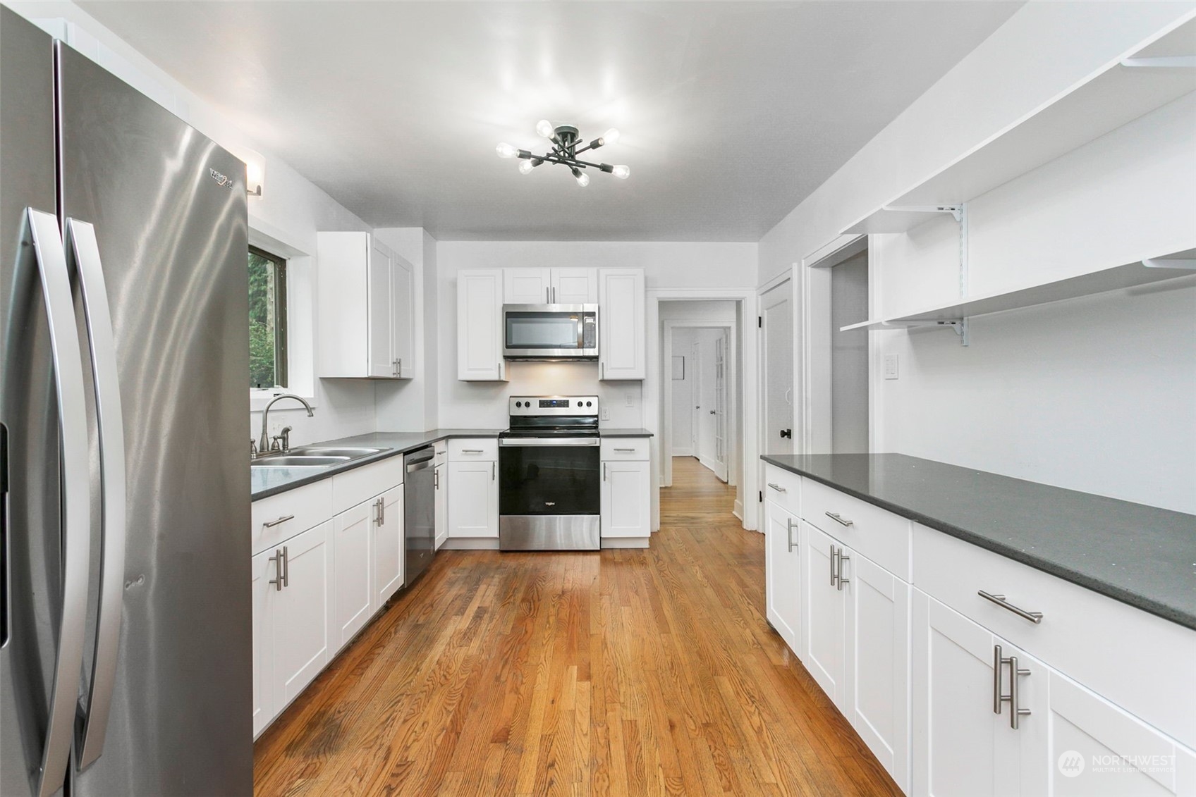 710 Prospect Avenue North Kent, WA 98031 - Photo 10 of 37 a kitchen with granite countertop a refrigerator a stove a sink and white cabinets with wooden floor