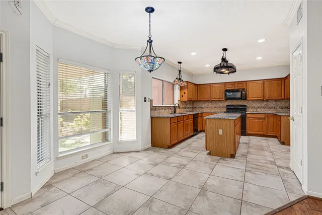a large kitchen with stainless steel appliances kitchen island granite countertop a stove a sink and a refrigerator