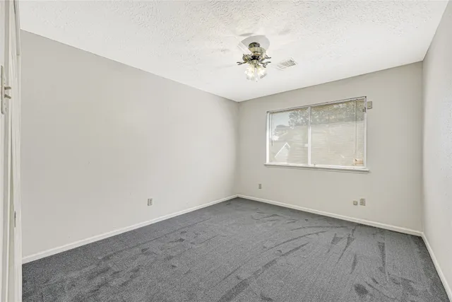an empty room with a window and ceiling fan