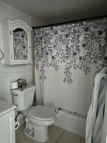 a bathroom with a toilet and a shower curtain