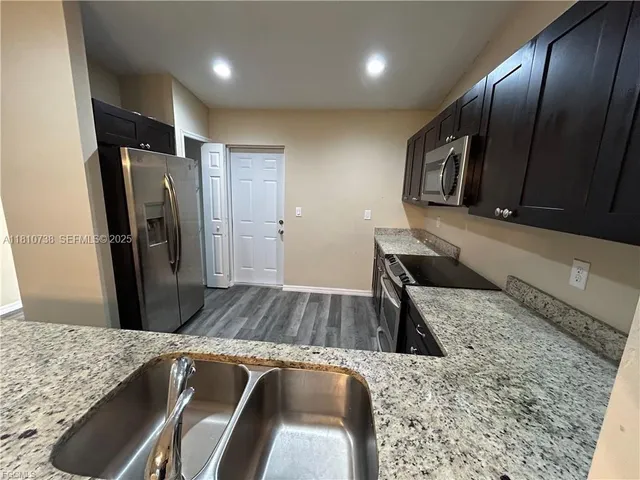 a view of kitchen with stainless steel appliances granite countertop sink and stove