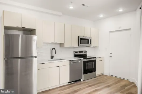 a kitchen with a refrigerator sink and white cabinets