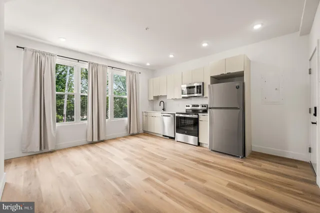 a kitchen with stainless steel appliances a refrigerator and wooden floor