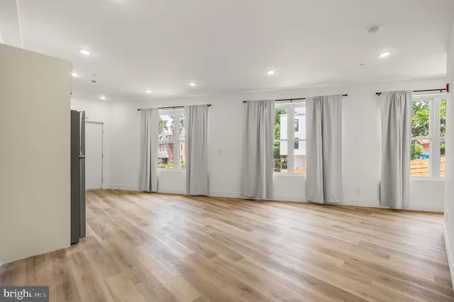 a view of an empty room with wooden floor and windows