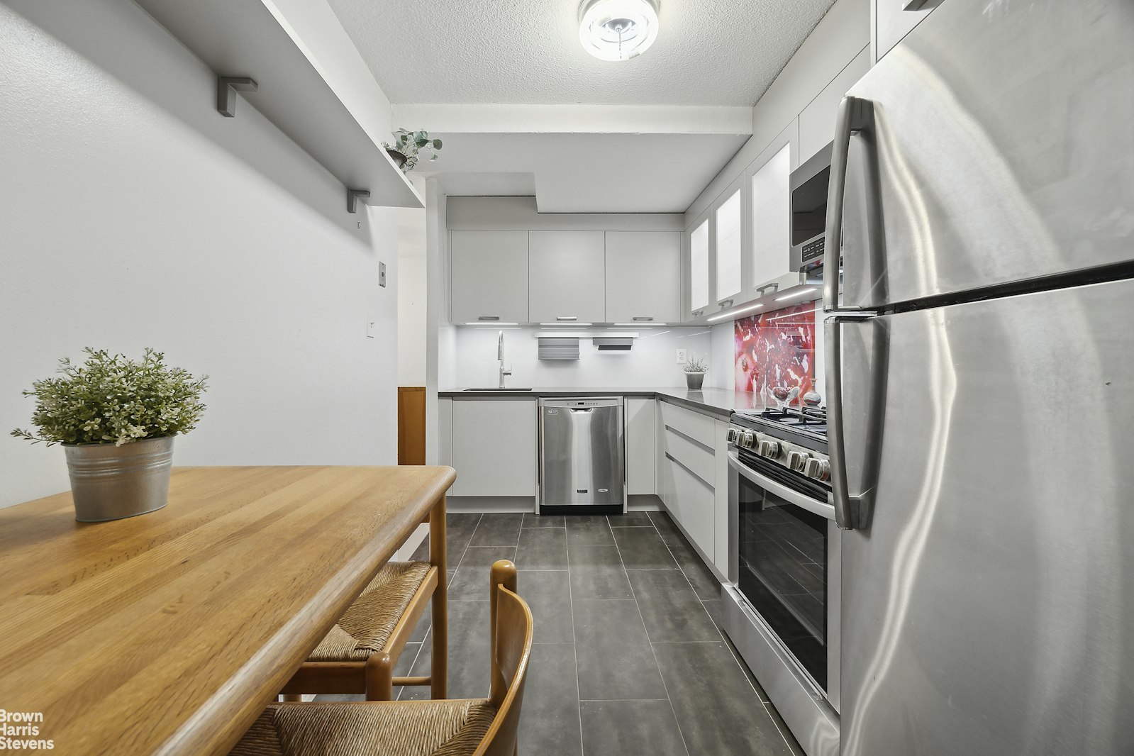 118-18 Union Turnpike, Unit 9B Queens, NY 11415 - Photo 3 of 9 a kitchen with stainless steel appliances a stove a sink dishwasher a refrigerator white cabinets and wooden floor