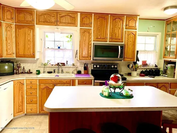 a kitchen with kitchen island granite countertop wooden cabinets a stove top oven a sink and dishwasher