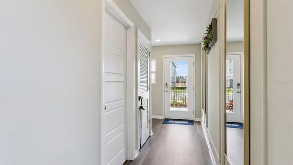a view of a hallway with wooden floor and a bathroom