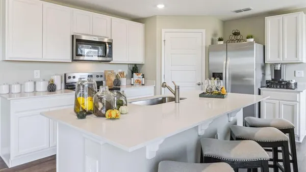 a kitchen with a refrigerator a sink a stove and chairs