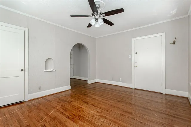 an empty room with wooden floor and ceiling fan