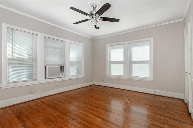 a view of an empty room with a window and wooden floor