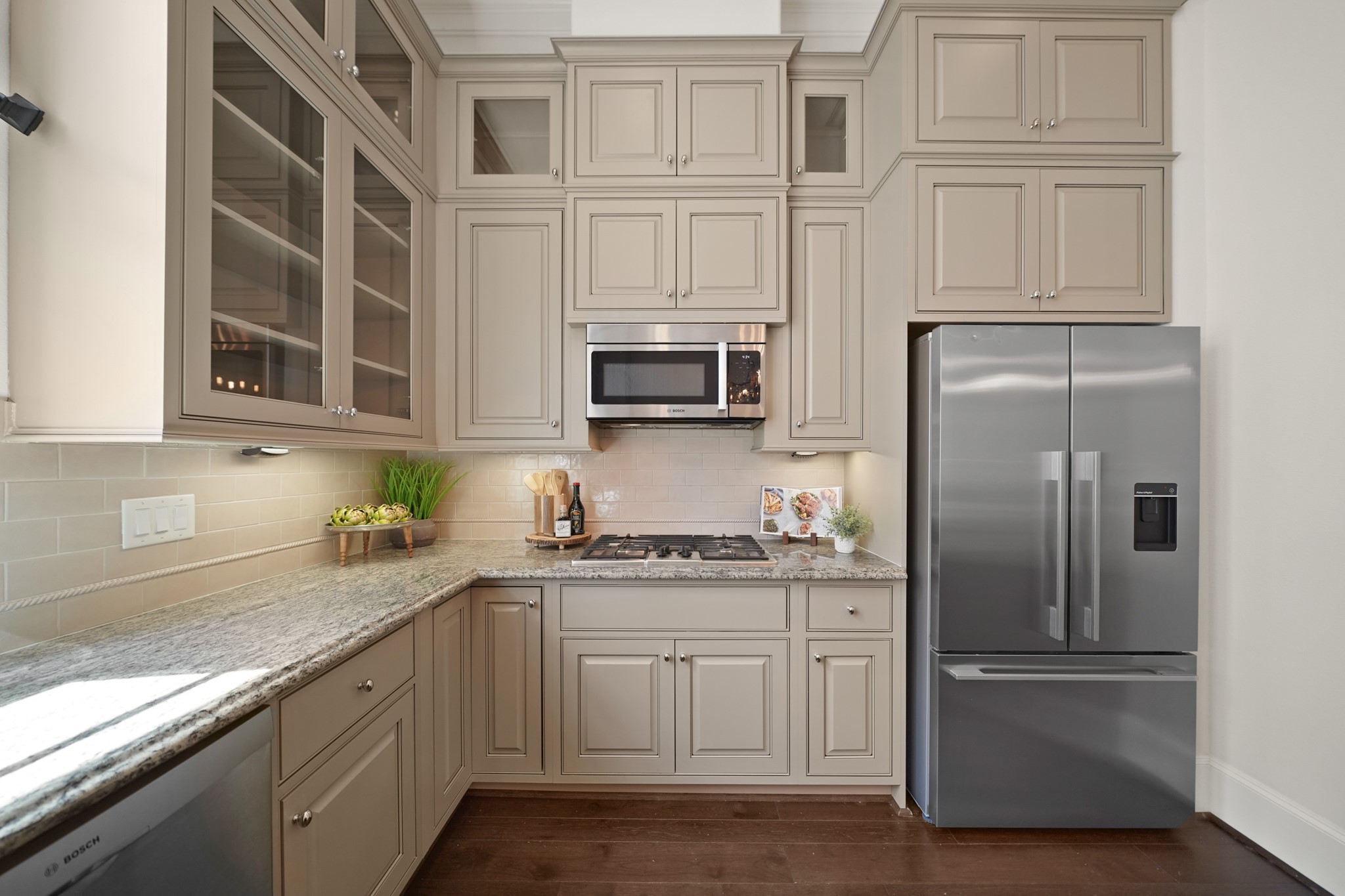 1317 Roy Street Houston, TX 77007 - Photo 16 of 50 Both stylish and functional, the kitchen features a Bosch oven, microwave and a four-burner gas cooktop. The decorative painted cabinets with black trim and satin nickel hardware includes glass display cabinets and a second row of upper cabinets. Subway tile backsplash with a decorative rope accent adds a touch of elegance.