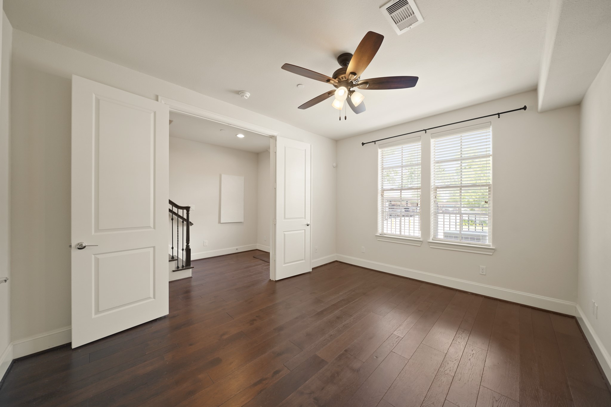 1317 Roy Street Houston, TX 77007 - Photo 45 of 50 The fourth bedroom, located on the first floor, features hardwood floors, a ceiling fan with lights and windows with blinds ready for your curtains to be hung.