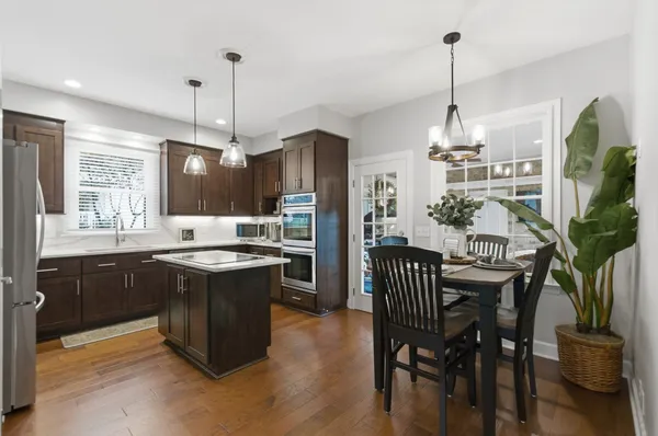 a kitchen with stainless steel appliances granite countertop a stove a sink a refrigerator a dining table and chairs