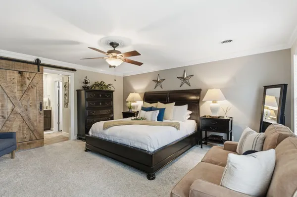a bedroom with a bed couch chandelier and a window