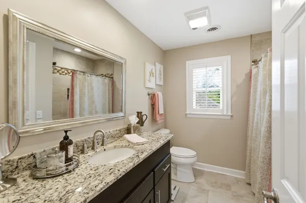 a bathroom with a granite countertop sink a toilet and a mirror