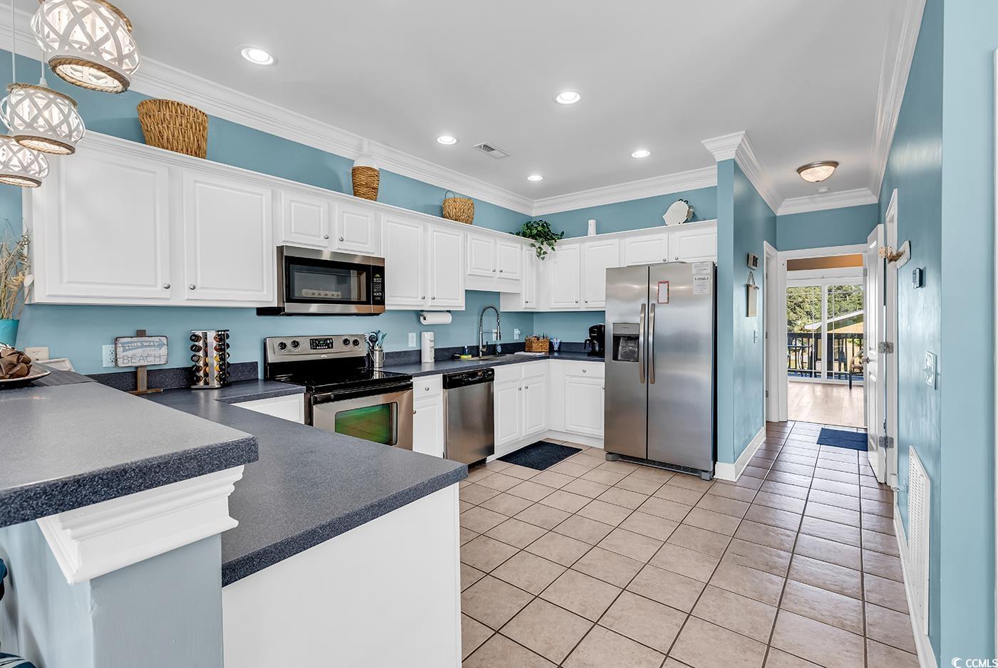 124 B Vista Drive Murrells Inlet, SC 29576 - Photo 12 of 38 Kitchen featuring stainless steel appliances, dark countertops, crown molding, white cabinetry, and light tile patterned floors