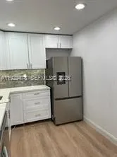 a kitchen with granite countertop white cabinets and stainless steel appliances