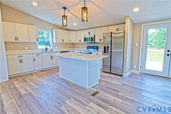 a kitchen with kitchen island wooden floors appliances and cabinets
