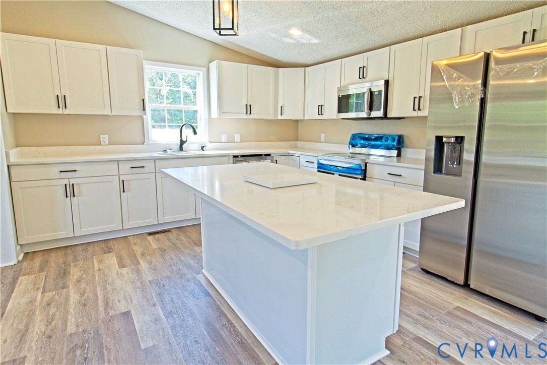 2110 Military Road Amelia Court House, VA 23002 - Photo 14 of 46 a kitchen with kitchen island a sink cabinets and wooden floor