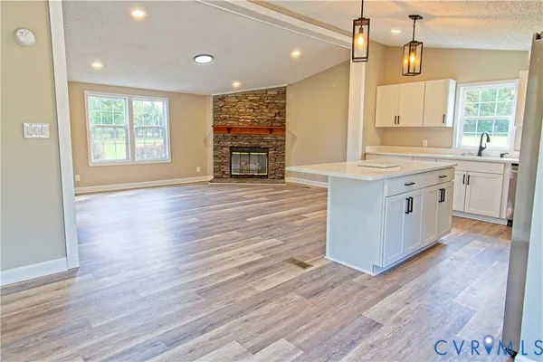 a large kitchen with granite countertop a large counter top space wooden floor and stainless steel appliances
