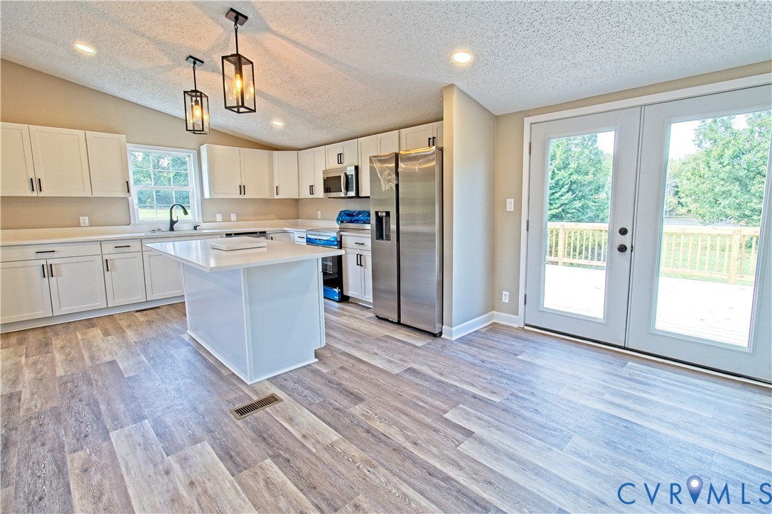 2110 Military Road Amelia Court House, VA 23002 - Photo 17 of 46 a kitchen with stainless steel appliances granite countertop a stove a refrigerator a sink and white cabinets with wooden floor next to windows