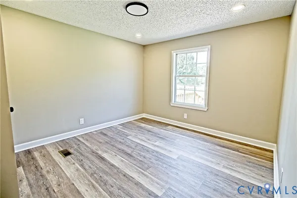an empty room with wooden floor and window