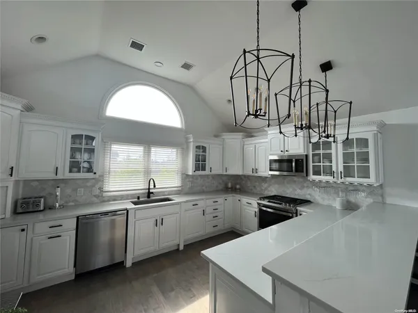 a kitchen with stainless steel appliances a sink a stove a refrigerator and cabinets