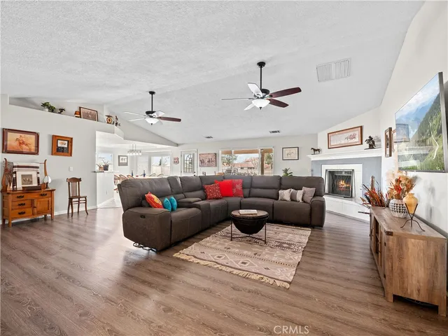 a living room with furniture kitchen view and a wooden floor