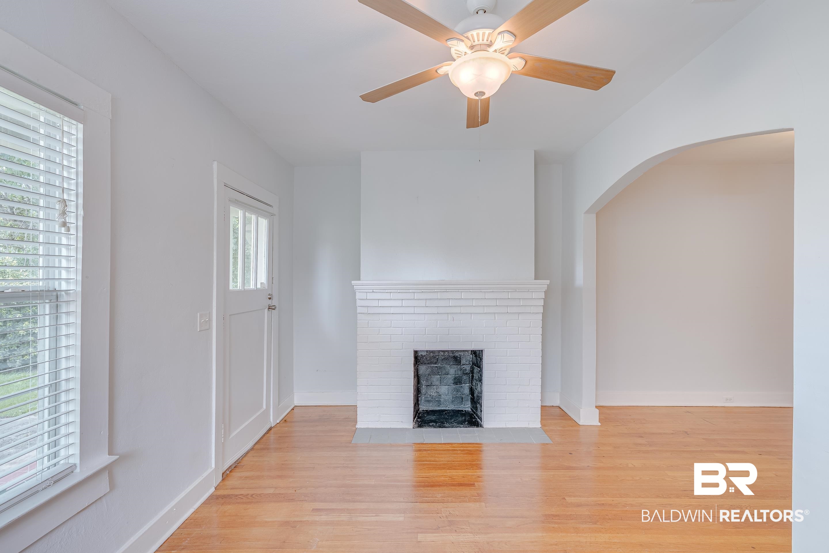 1852 Old Shell Road Mobile, AL 36607 - Photo 6 of 26 Unfurnished living room featuring arched walkways, wood finished floors, a fireplace, and ceiling fan