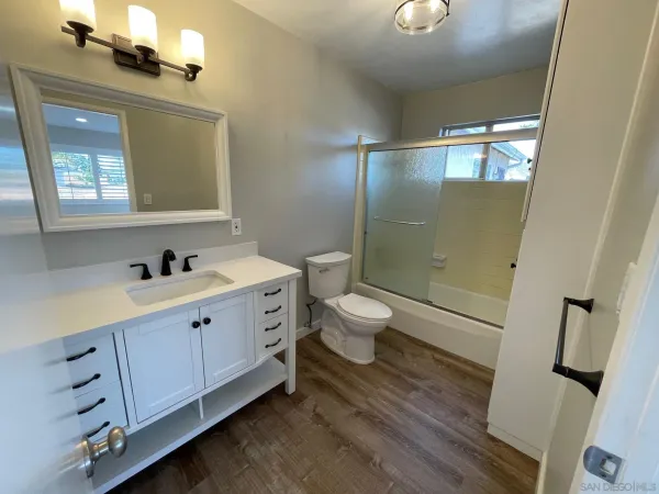 a bathroom with a double vanity sink and mirror with toilet