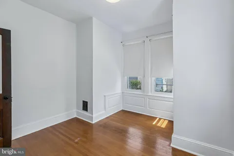 a view of an empty room with window and wooden floor