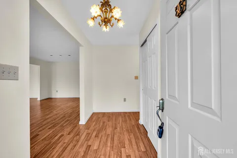a view of a hallway with wooden floor and a chandelier