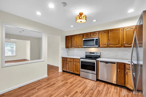 a kitchen with stainless steel appliances granite countertop a sink a stove a microwave and wooden floors