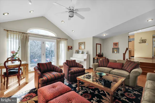 a living room with furniture a ceiling fan and a large window