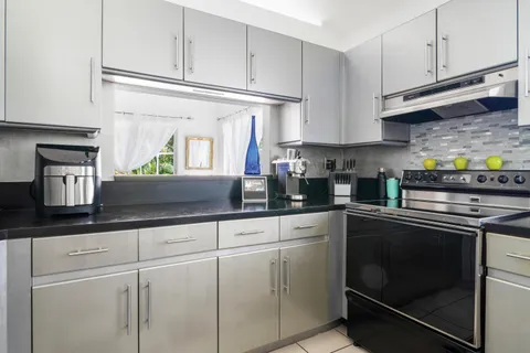 a kitchen with granite countertop white cabinets stainless steel appliances and sink