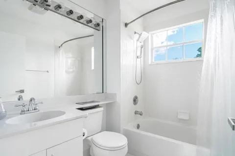 a bathroom with a bathtub shower sink vanity and toilet