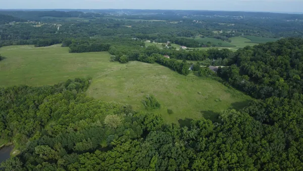 an aerial view of residential house with outdoor space and trees all around