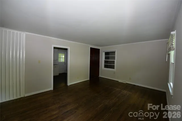 an empty room with wooden floor closet and windows