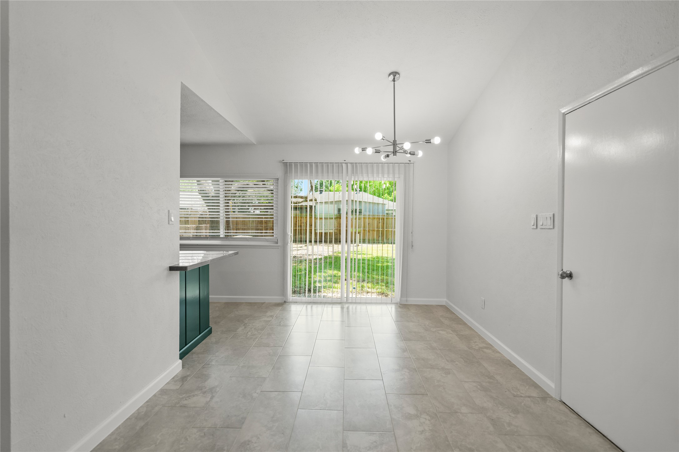 6610 Blue Ridge Drive Richmond, TX 77469 - Photo 5 of 24 Bright dining area with sleek tile flooring, modern lighting, and sliding glass doors leading to a backyard. Open layout with a view into the kitchen featuring a breakfast bar.