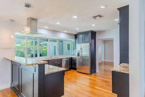 a kitchen with stainless steel appliances granite countertop a refrigerator and a sink