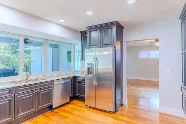 a kitchen with kitchen island granite countertop wooden cabinets and a refrigerator