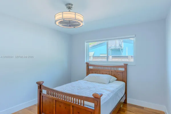 an empty room with wooden floor chandelier fan and windows
