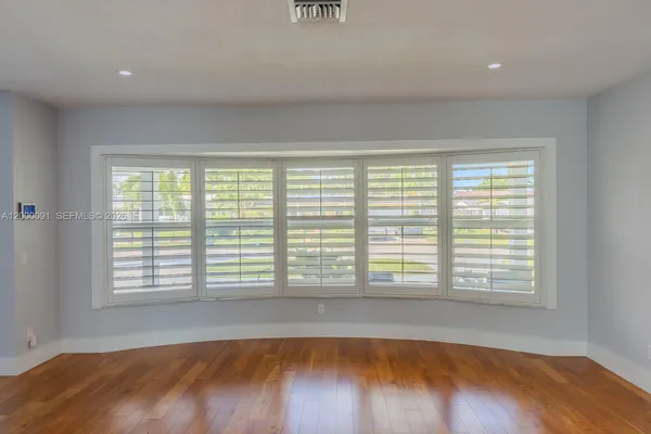 a view of a kitchen with kitchen island a sink wooden floor and a large window