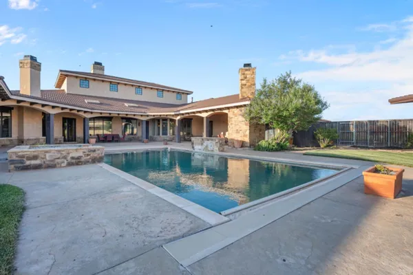 a view of house with swimming pool and a yard