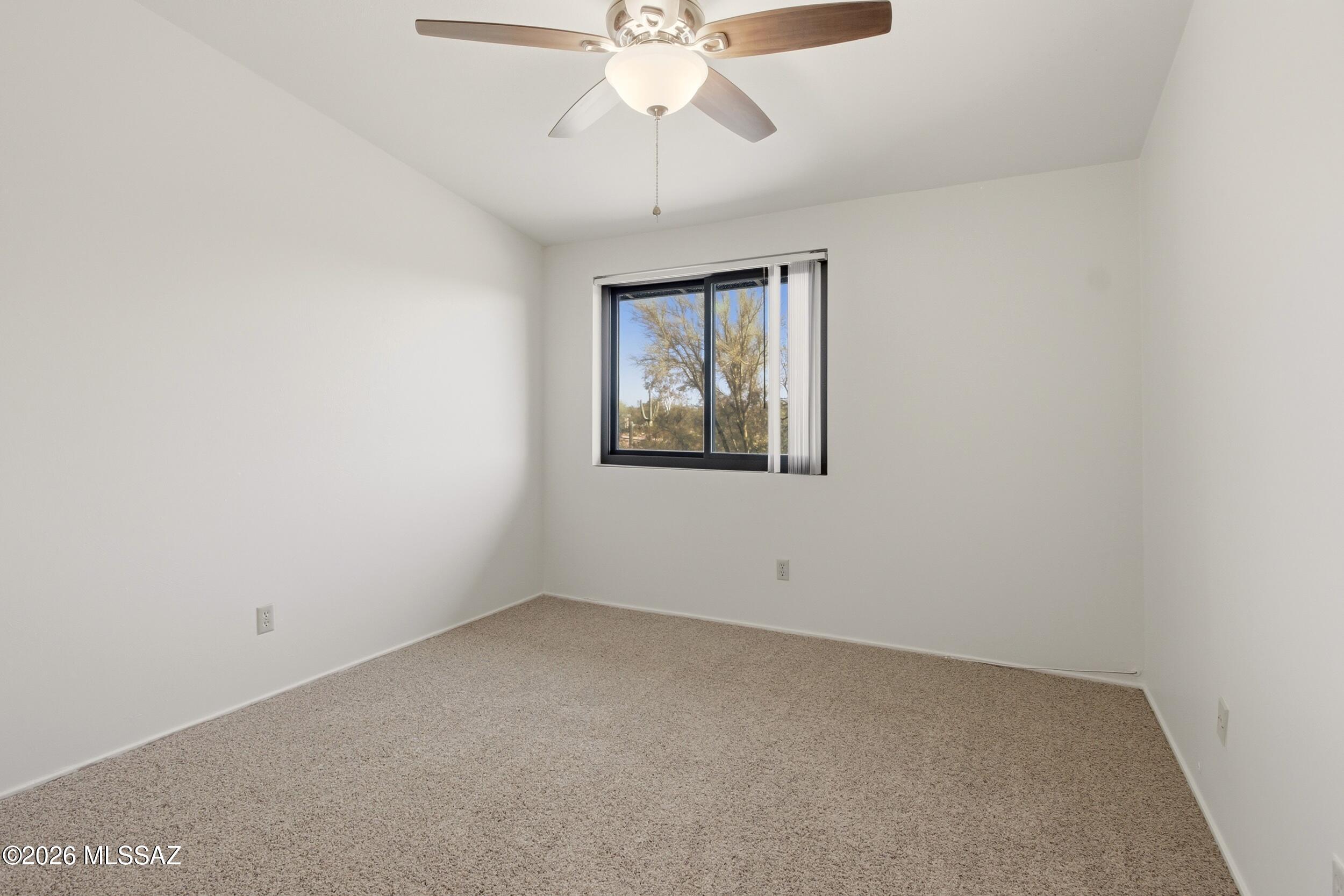 9141 East Indian Canyon Road Tucson, AZ 85749 - Photo 22 of 33 an empty room with a chandelier fan and windows